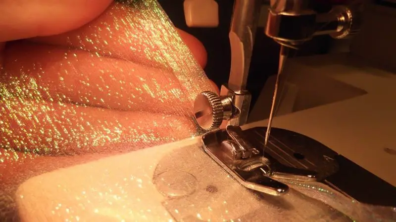 Hoe de achteruitknop op een naaimachine te repareren